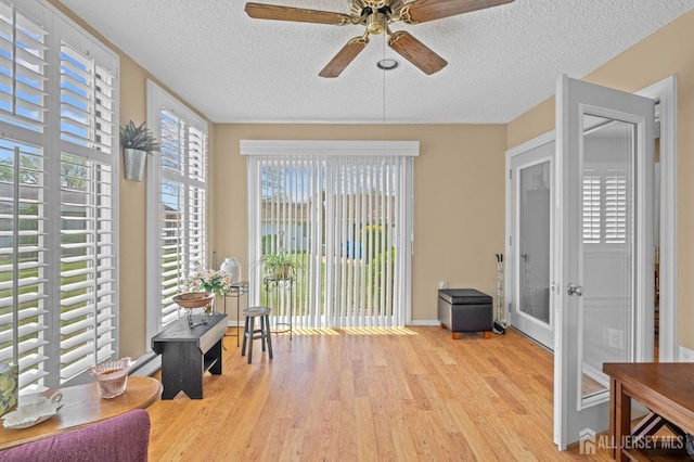 sitting room with a textured ceiling, wood finished floors, ceiling fan, french doors, and baseboards