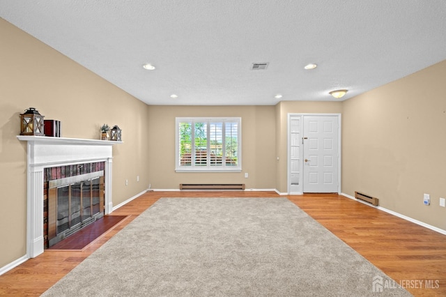 unfurnished living room featuring baseboard heating, a fireplace with flush hearth, wood finished floors, and recessed lighting