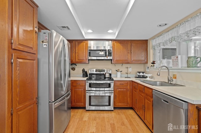 kitchen with appliances with stainless steel finishes, a sink, brown cabinets, and recessed lighting