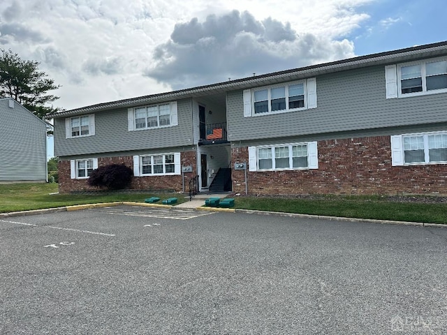 view of front facade with uncovered parking and brick siding