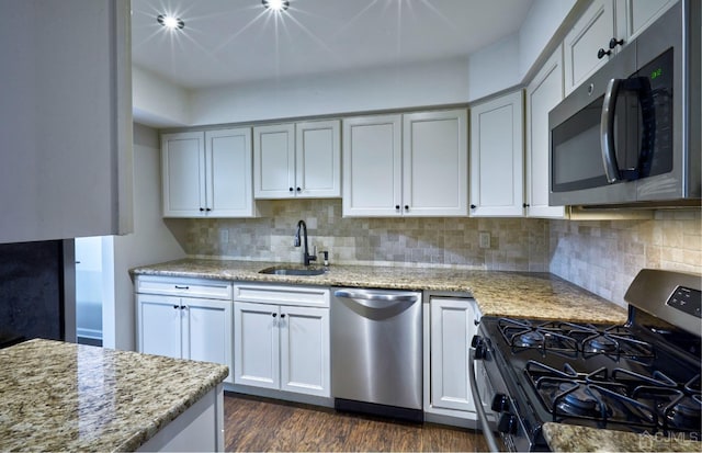 kitchen with sink, appliances with stainless steel finishes, decorative backsplash, and dark hardwood / wood-style floors