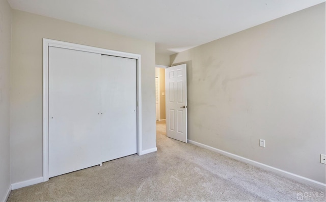 unfurnished bedroom featuring light carpet and a closet