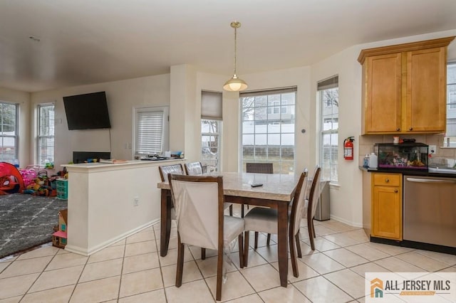 dining space featuring plenty of natural light, light tile patterned flooring, and baseboards