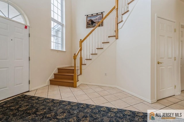 foyer with light tile patterned flooring, stairway, and baseboards