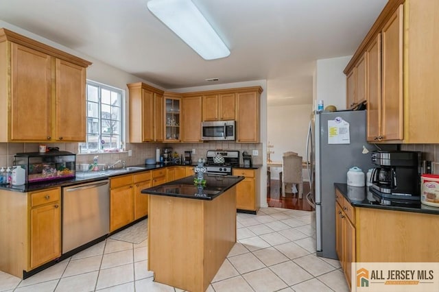 kitchen featuring light tile patterned floors, tasteful backsplash, appliances with stainless steel finishes, and a sink