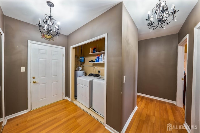 laundry area featuring water heater, a chandelier, washer and dryer, and light wood-type flooring