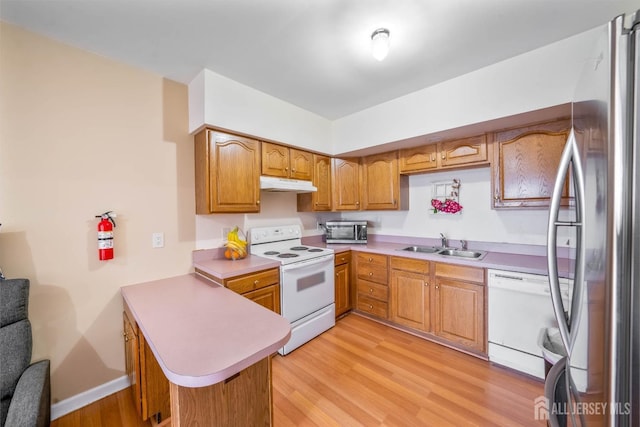 kitchen with sink, light hardwood / wood-style flooring, kitchen peninsula, and appliances with stainless steel finishes