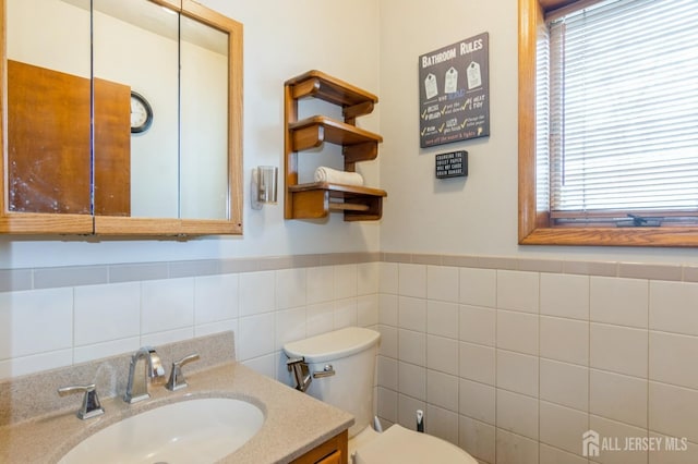 40 Riverview Ave, Piscataway, NJ 08854 - bathroom featuring toilet, vanity, plenty of natural light, tile walls, and wainscoting