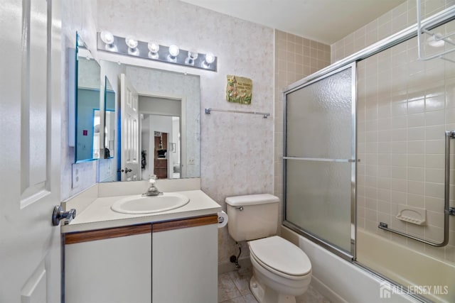 bathroom with toilet, tile patterned flooring, vanity, and shower / bath combination with glass door