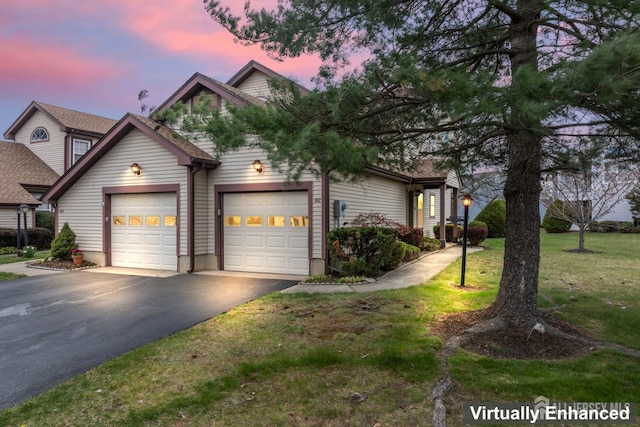 view of front of home with a front yard, aphalt driveway, and an attached garage
