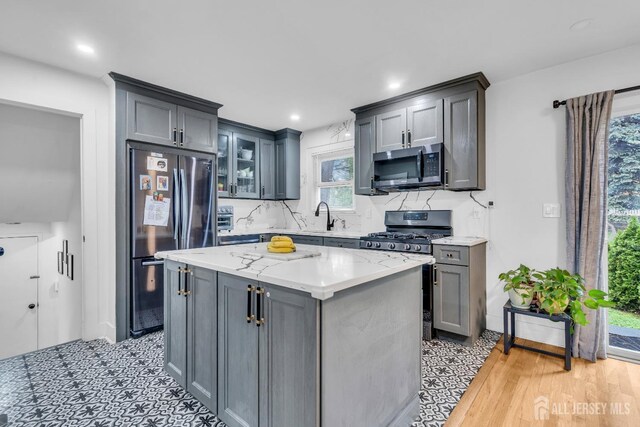 374 Nottingham Way, Union Twp, NJ 07083 - kitchen featuring stainless steel appliances, gray cabinetry, tasteful backsplash, a kitchen island, and light stone countertops