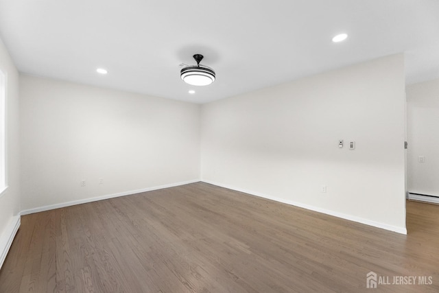 empty room with dark hardwood / wood-style flooring and baseboard heating