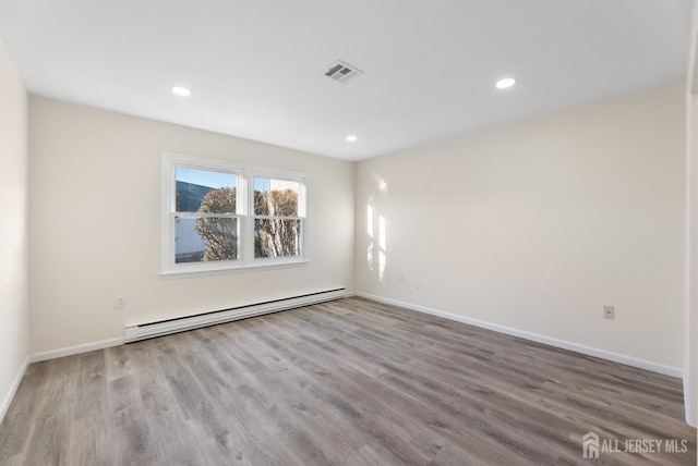 spare room featuring a baseboard heating unit and light hardwood / wood-style flooring