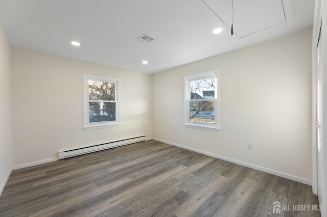 empty room featuring dark hardwood / wood-style flooring and a baseboard heating unit