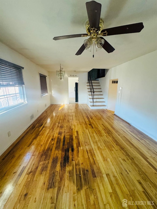 19 Spruce St, Port Reading, NJ 07064 - unfurnished living room with hardwood / wood-style flooring, stairs, a ceiling fan, and a chandelier