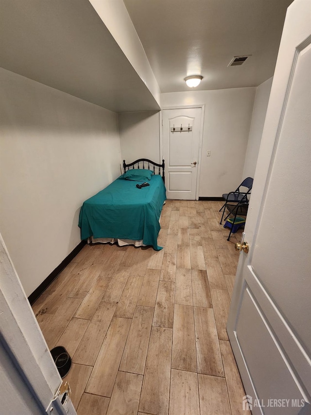 bedroom featuring light wood-style floors, visible vents, and baseboards