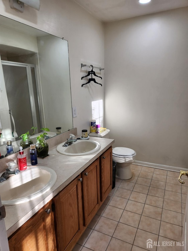 bathroom featuring tile patterned flooring, a shower stall, double vanity, and a sink