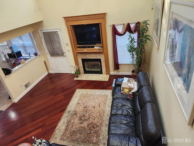 living room with visible vents, a fireplace with flush hearth, baseboards, and wood finished floors