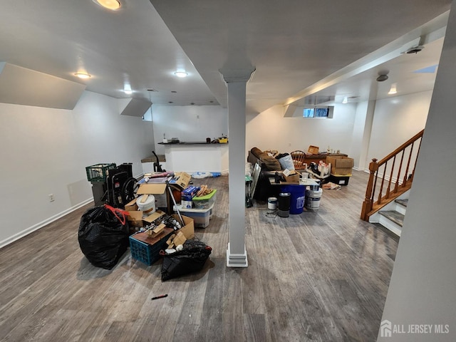 finished below grade area featuring stairs, wood finished floors, and baseboards