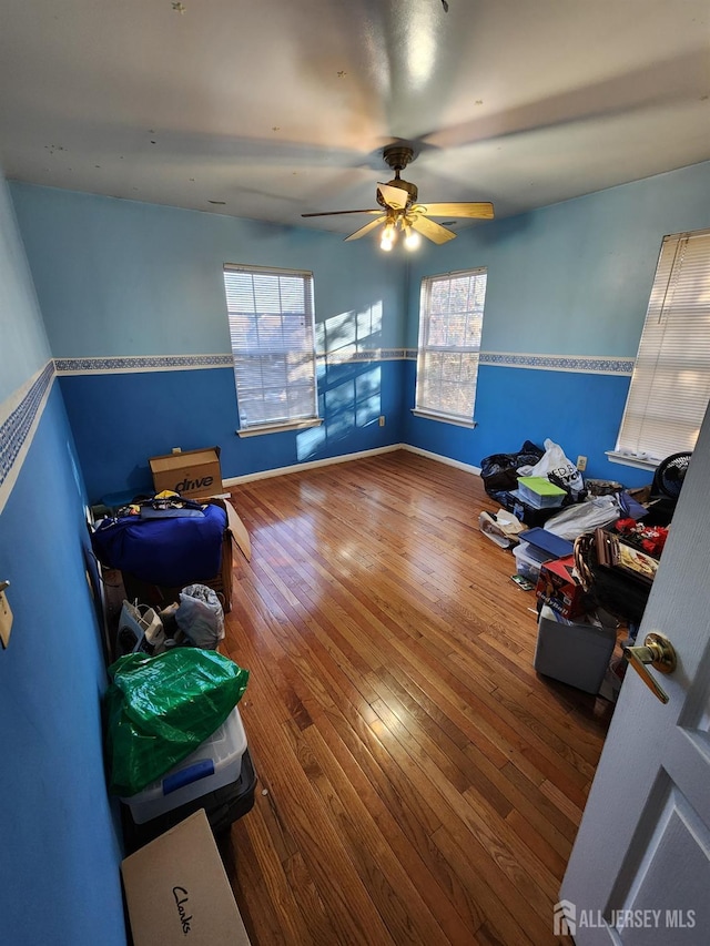 bedroom with hardwood / wood-style floors, multiple windows, baseboards, and ceiling fan