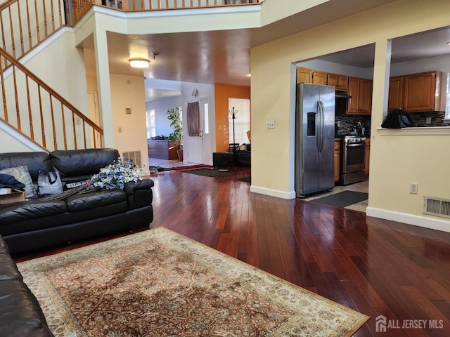 living room featuring dark wood-style floors, visible vents, stairs, and baseboards