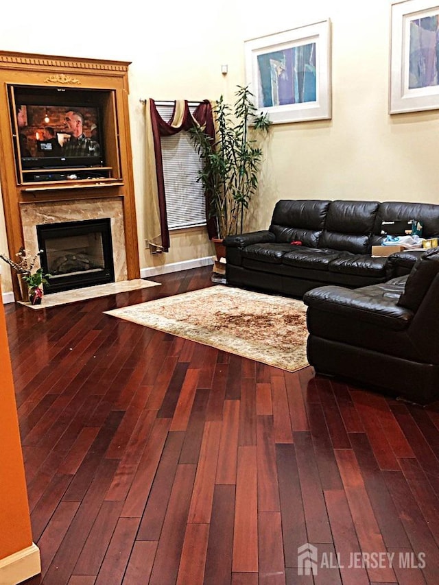 living room featuring a fireplace with flush hearth and dark wood-style floors