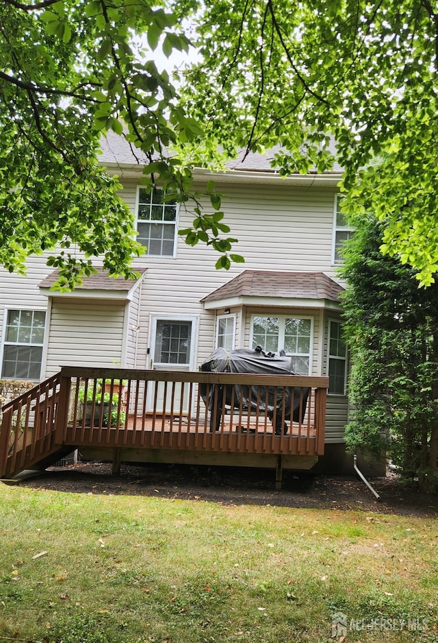 back of property featuring a wooden deck and a lawn