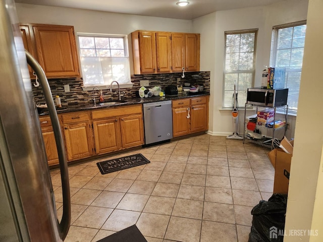 kitchen with light tile patterned flooring, decorative backsplash, stainless steel appliances, and a sink