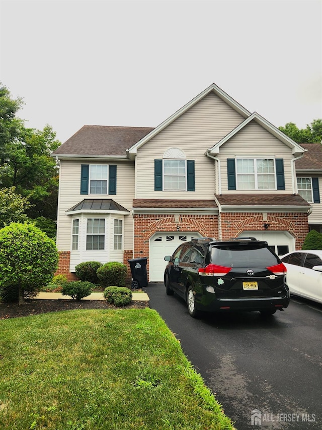 view of front of home with aphalt driveway, an attached garage, and brick siding