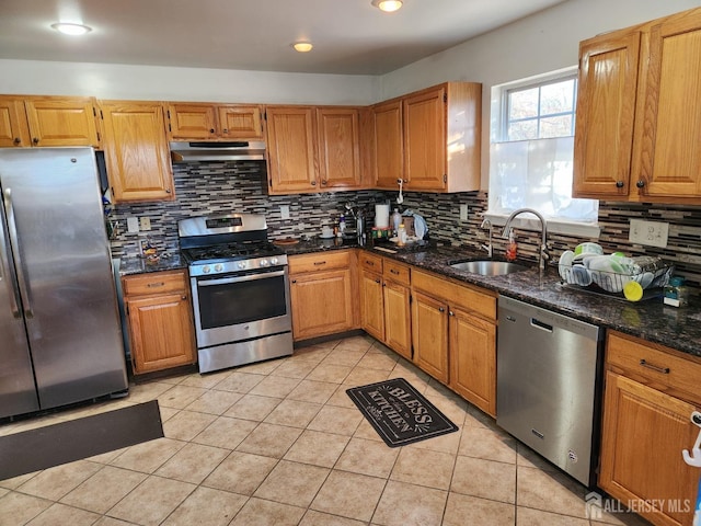 kitchen featuring tasteful backsplash, exhaust hood, light tile patterned flooring, stainless steel appliances, and a sink