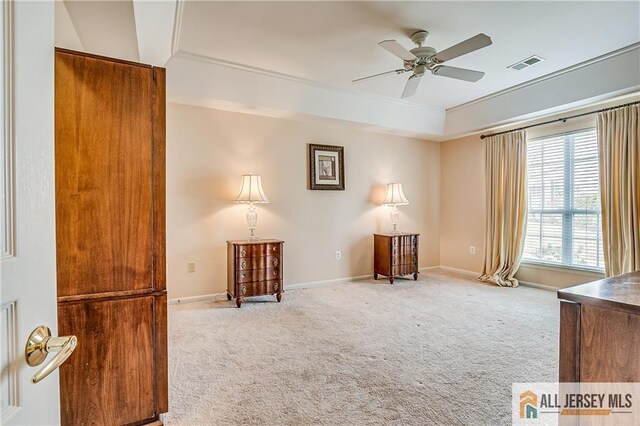 unfurnished room with ceiling fan, a tray ceiling, carpet, and visible vents