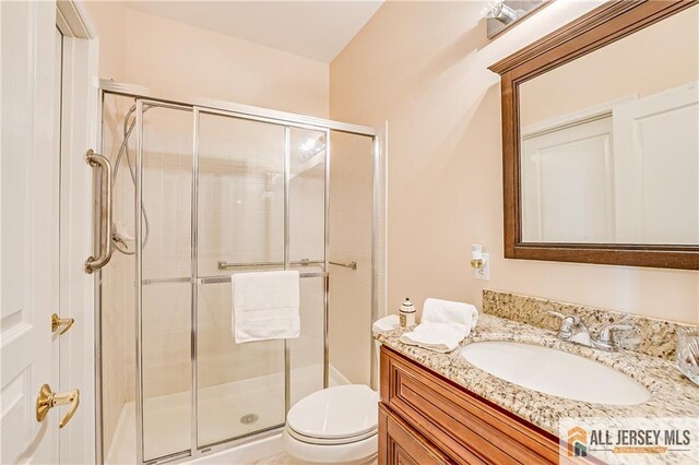 bathroom featuring toilet, a shower stall, and vanity