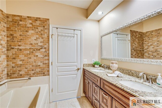 full bathroom with double vanity, a washtub, and a sink