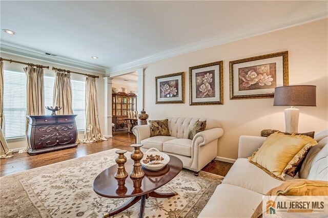 living area featuring ornamental molding, visible vents, ornate columns, and wood finished floors