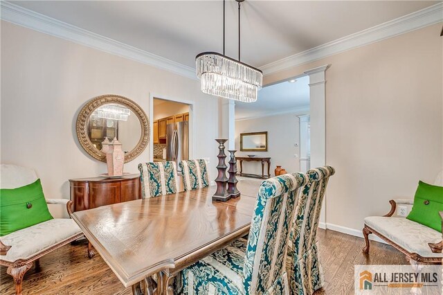 dining area featuring decorative columns, an inviting chandelier, ornamental molding, light wood-type flooring, and baseboards