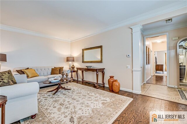 living area featuring crown molding, baseboards, and wood finished floors