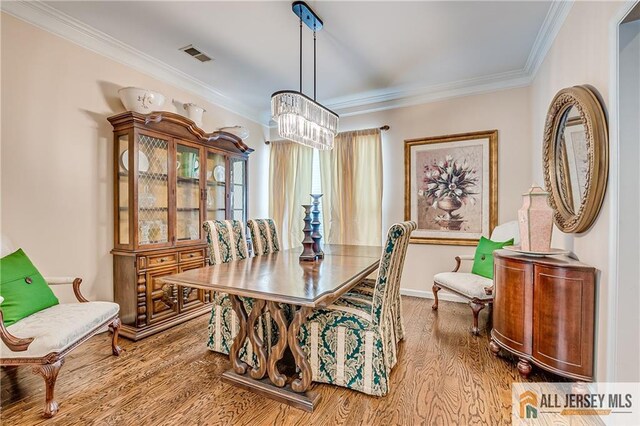 dining space featuring light wood finished floors, baseboards, visible vents, and crown molding