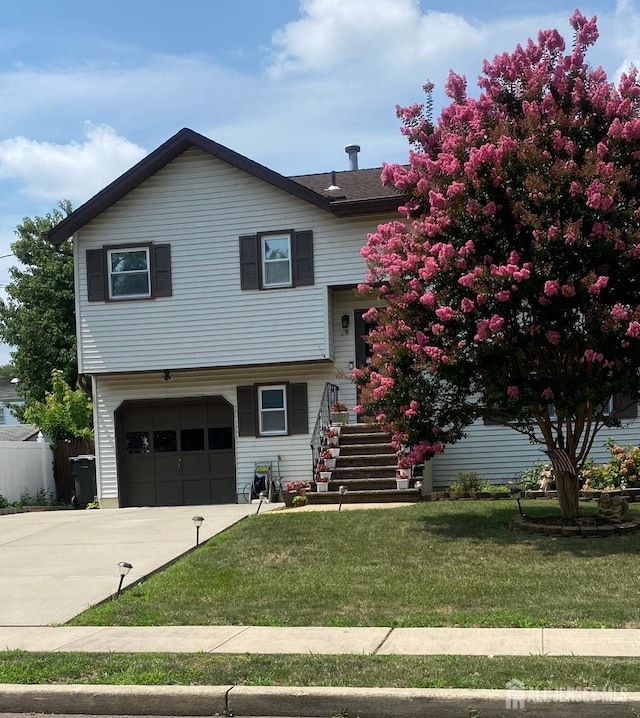 tri-level home with a front yard, driveway, an attached garage, and stairs