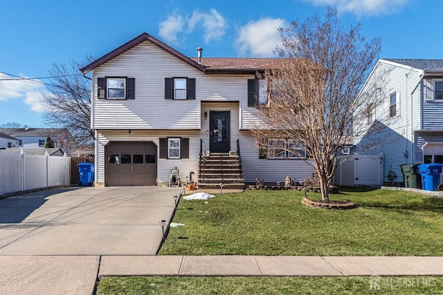 split foyer home with a garage, driveway, a front yard, and fence