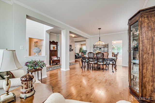 dining room with light wood finished floors, baseboards, and ornamental molding