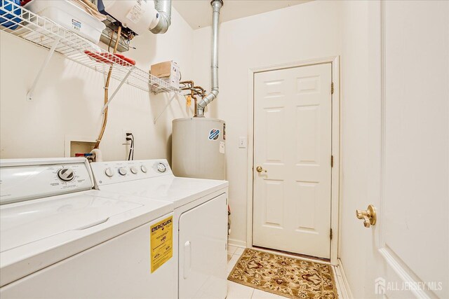 clothes washing area with water heater, washer and clothes dryer, and light tile patterned flooring