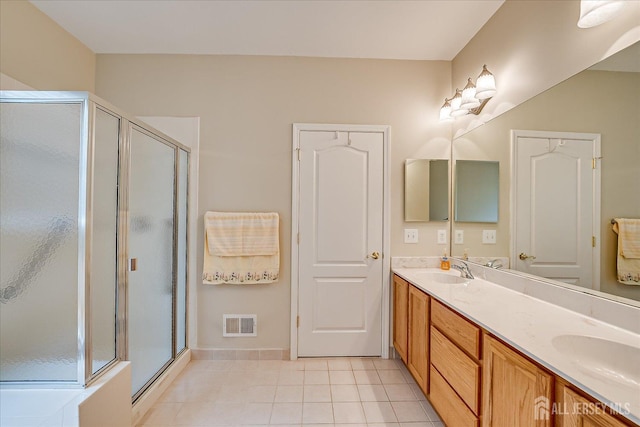 full bathroom with a stall shower, tile patterned flooring, double vanity, and baseboards
