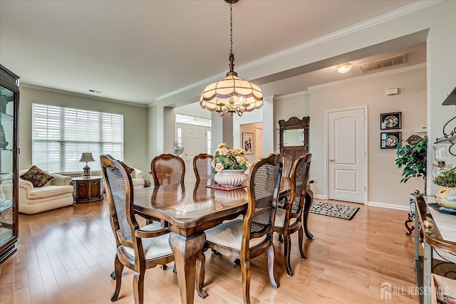 dining space with light wood-style floors, ornamental molding, a chandelier, and baseboards