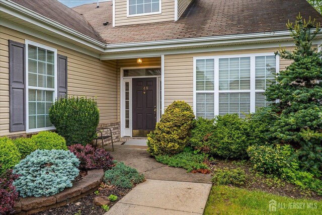 entrance to property featuring roof with shingles