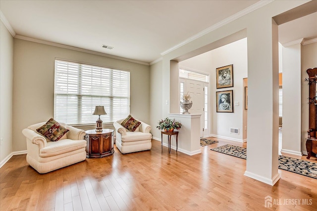 living area featuring light wood-style flooring, crown molding, and baseboards