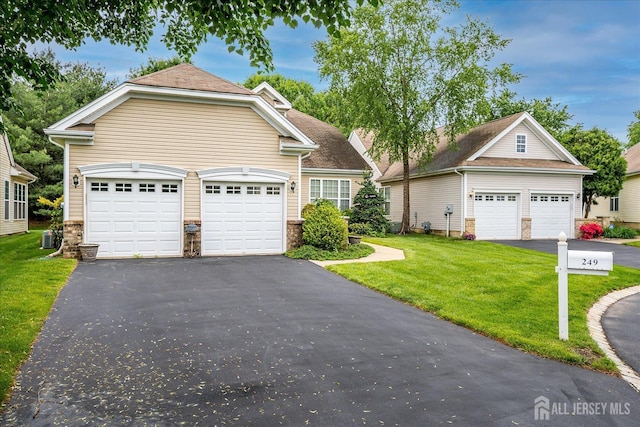 view of front facade with a front lawn, stone siding, and driveway