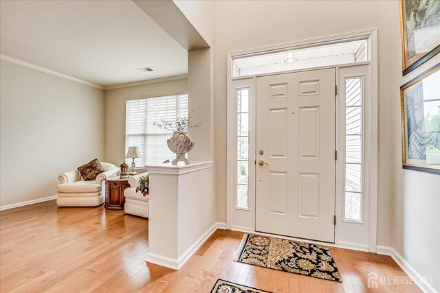 foyer entrance featuring light wood-type flooring, ornamental molding, and baseboards