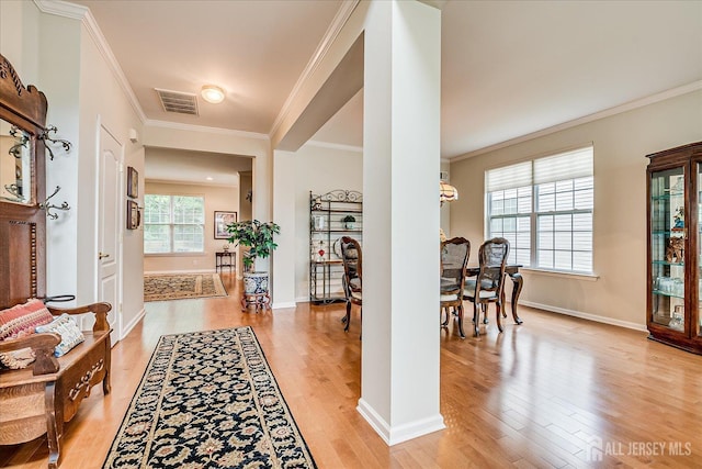 foyer entrance featuring crown molding, light wood-type flooring, and baseboards