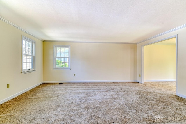 empty room with crown molding, carpet floors, and baseboards
