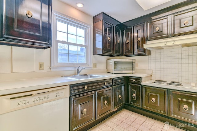 kitchen featuring light tile patterned flooring, a sink, white appliances, light countertops, and tasteful backsplash